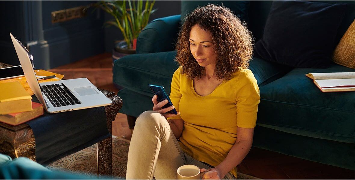 A millennial on their personal cell phone while enjoying coffee.