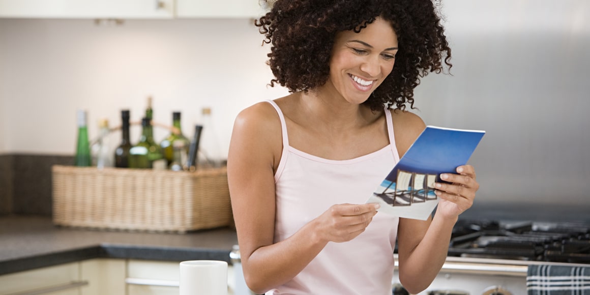 A woman reading a brochure in the kitchen.