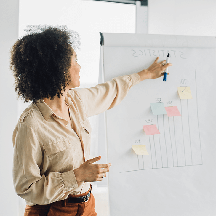 A woman presenting statistics off a large paper board.