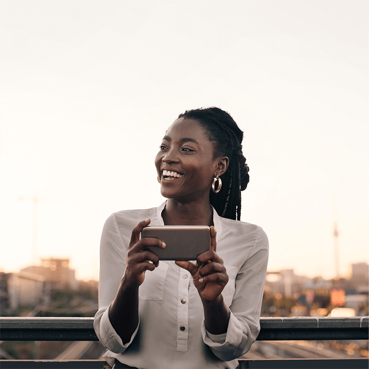 A woman laughing as she's engaged with her cell phone.