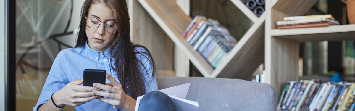 Woman in an office looking at her mobile phone.