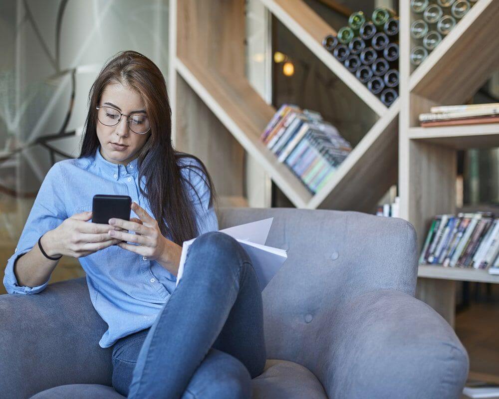 Woman in an office looking at her mobile phone.