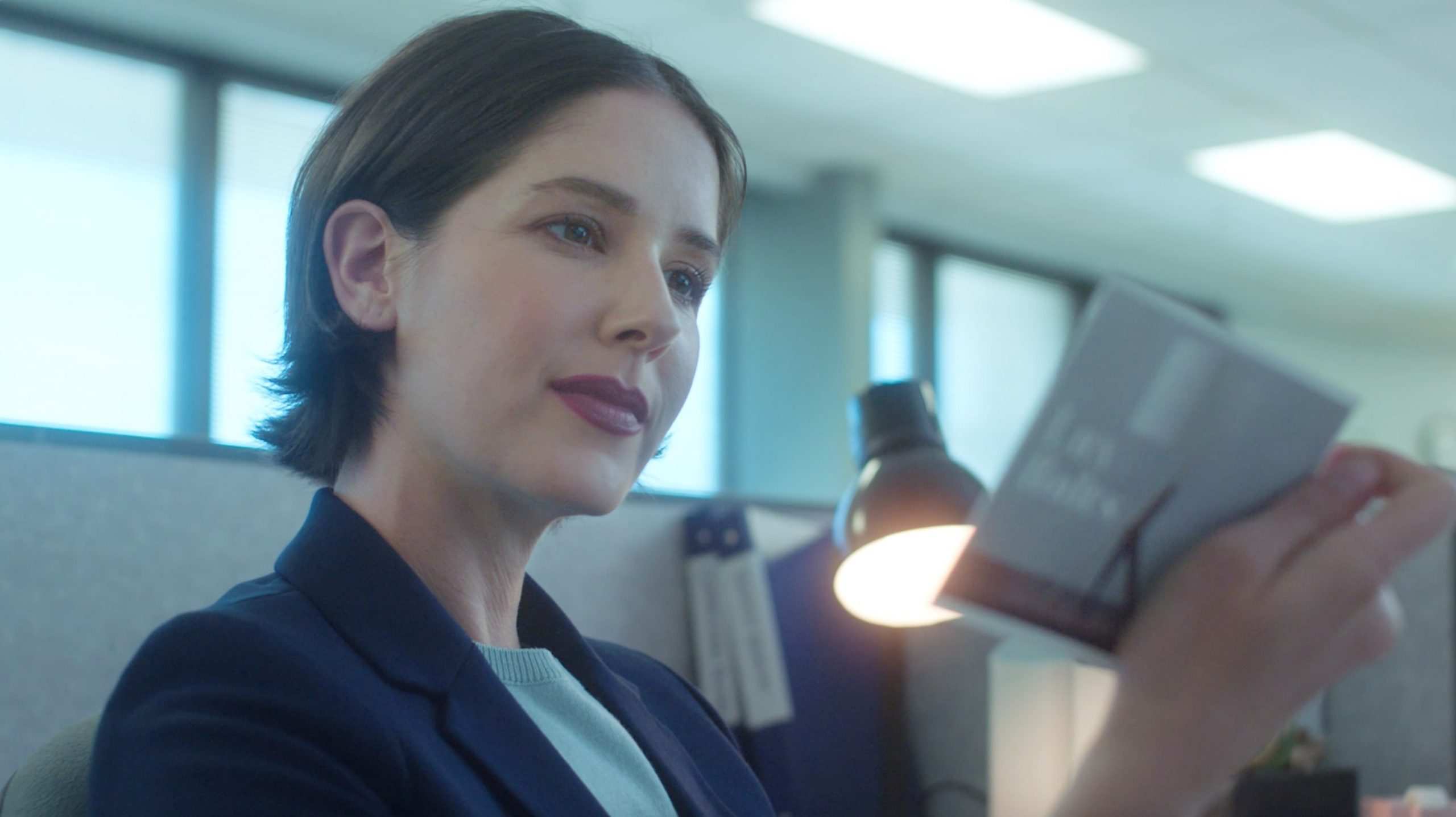 A woman reading a piece of marketing mail at her desk.