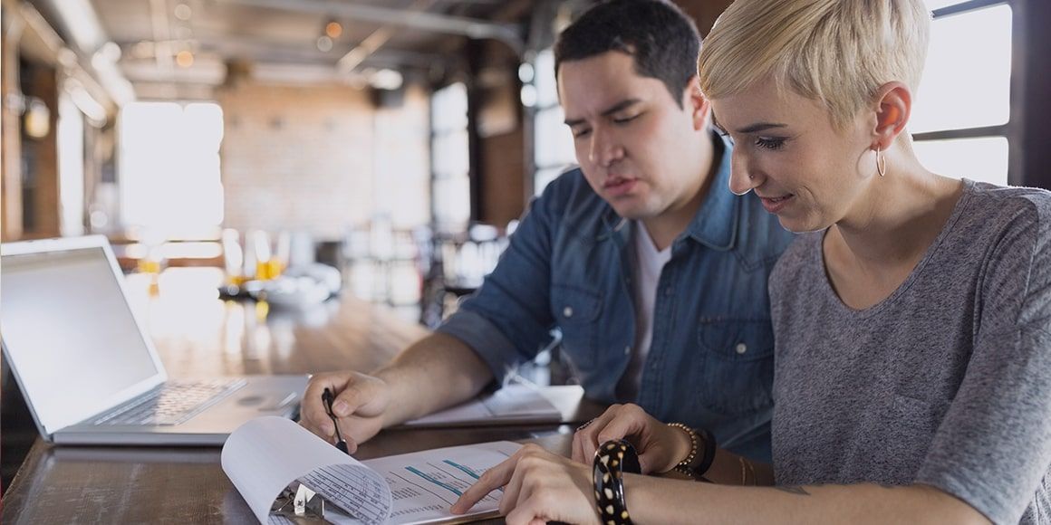 Two employees reading over a document together in the office.