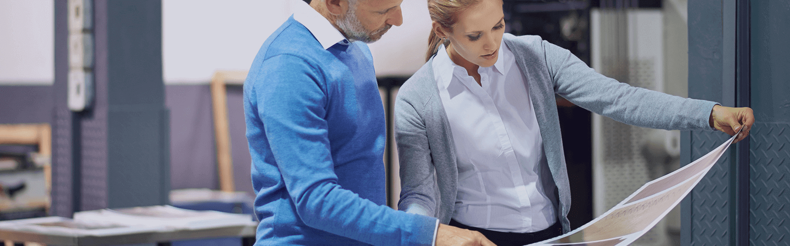 Two coworkers reviewing a large printout together.