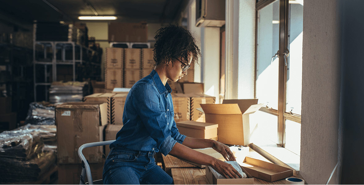 Woman sitting with an open box on her desk.