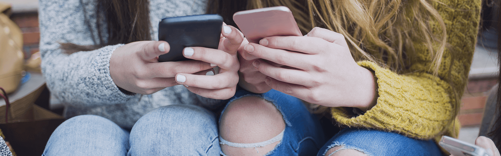 Two young women looking at their mobile phones together.