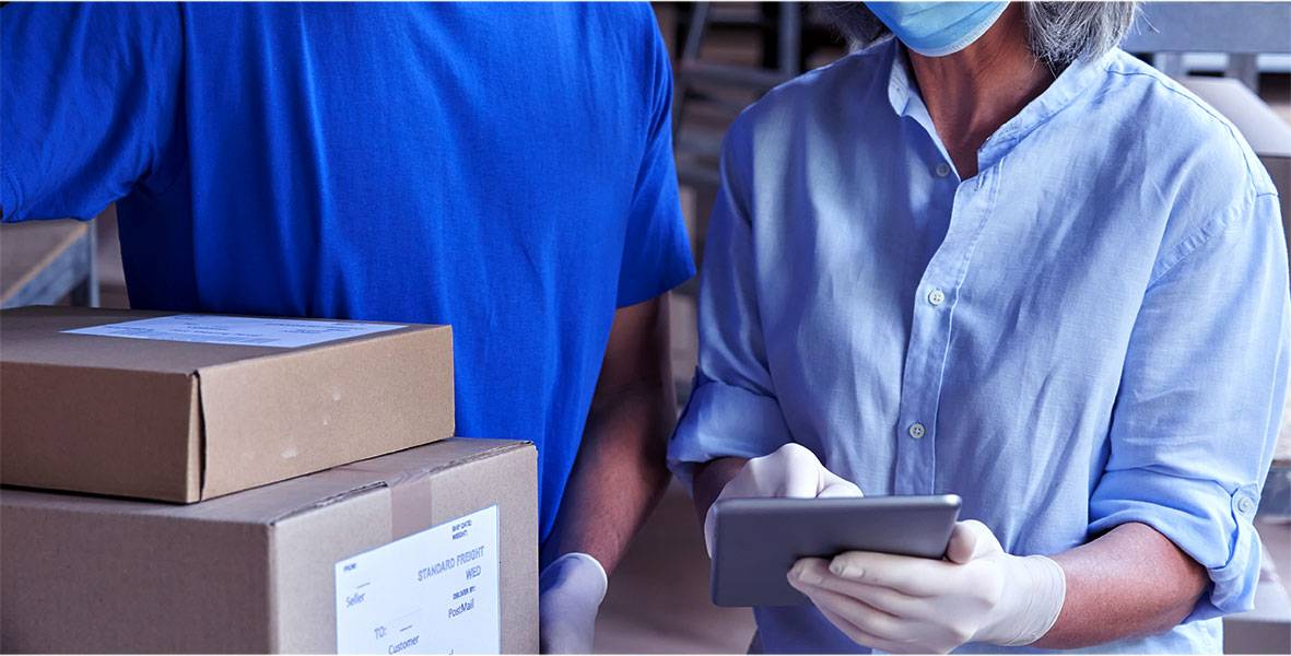 Retail manager with a tablet and phone inspecting inventory in a warehouse.
