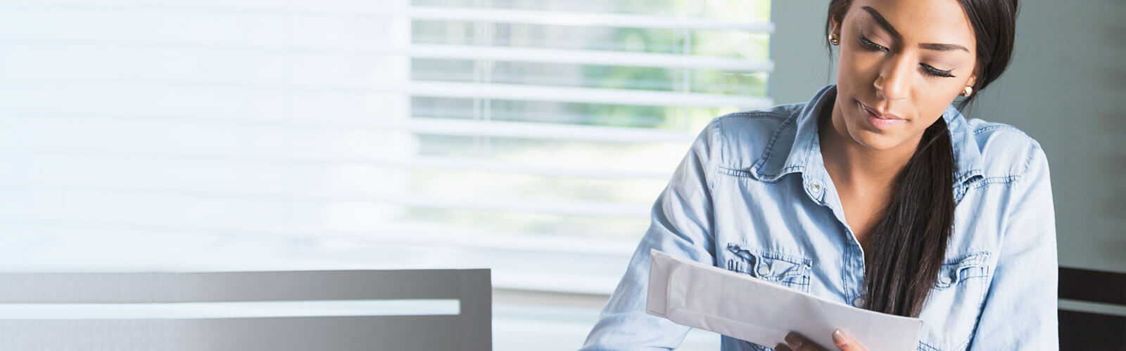 A woman sitting at a desk looking at direct mailpieces.