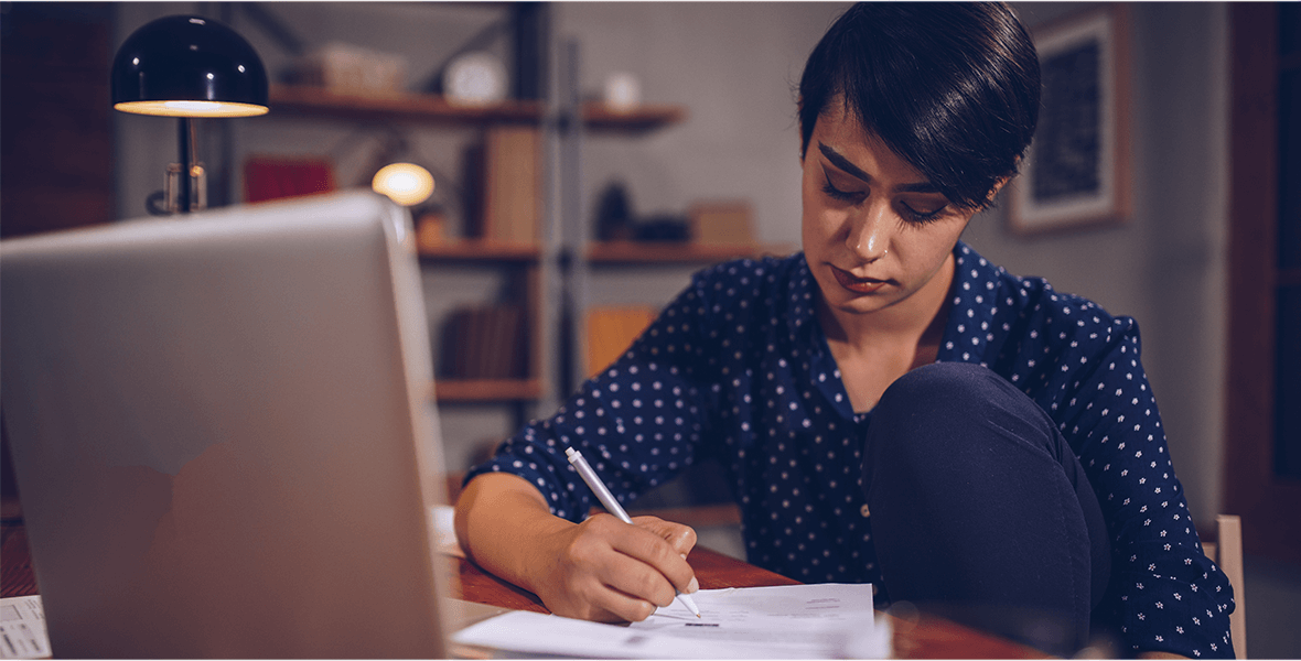 A woman sitting by her laptop doing paperwork.