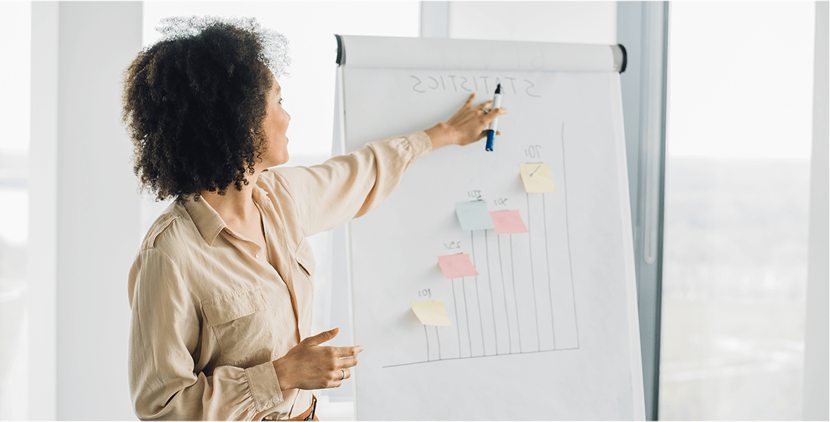 A woman presenting statistics off a large paper board.