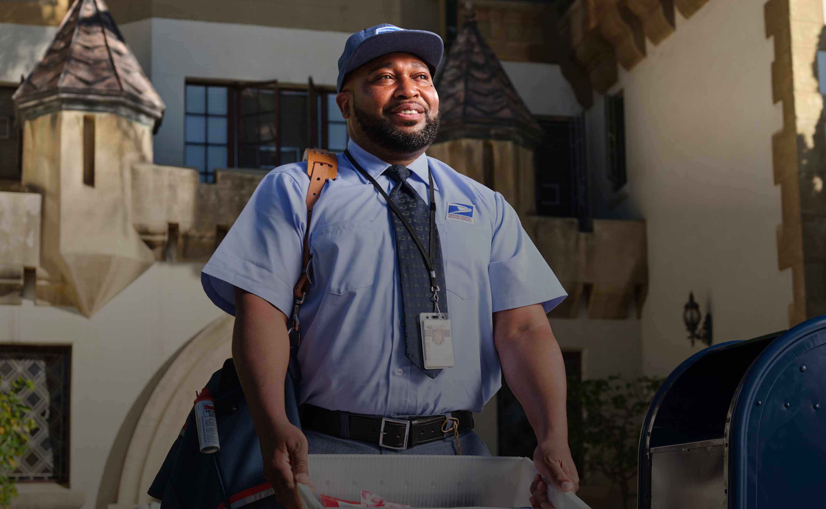 A smiling USPS carrier walking away from a delivery. Headline reads “Built for large. Built for small. Built to ship.”
