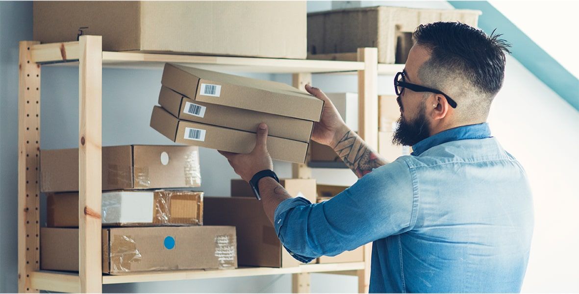 A photograph of a man stacking packages on a shelf.