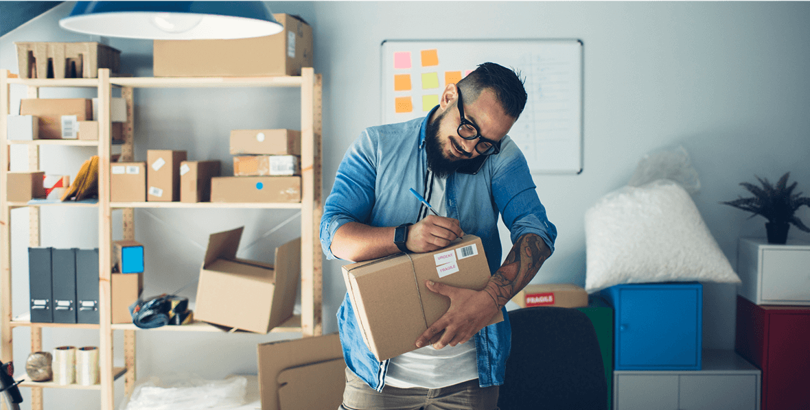 A man talking on his cell phone and writing on a package.