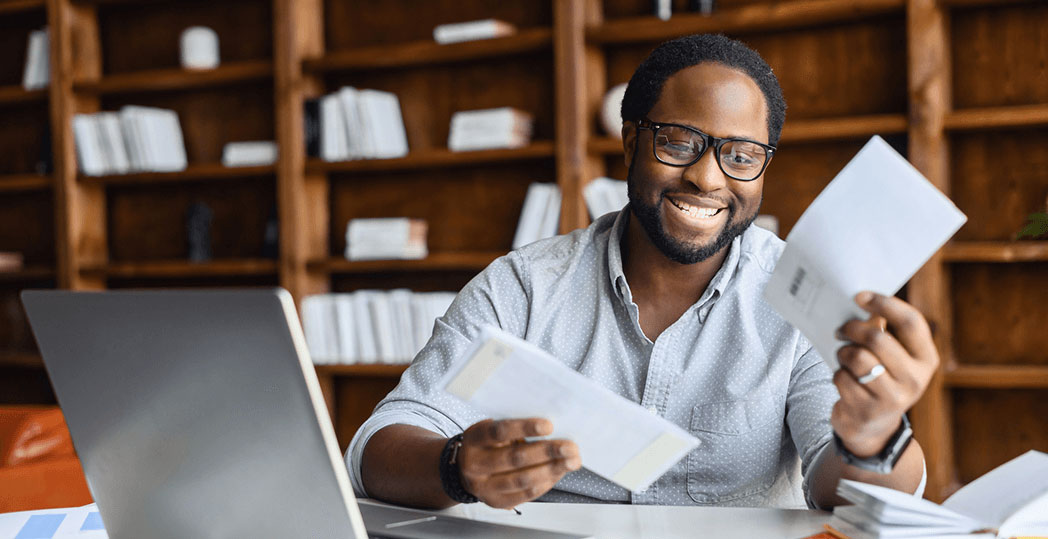Cheerful entrepreneur reads through a handful of mail items