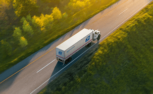 A United States Postal Service truck driving on a highway.