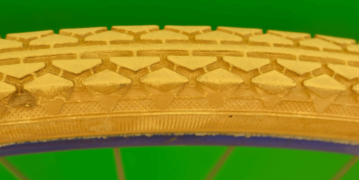 A close-up of a golden tire on green background.