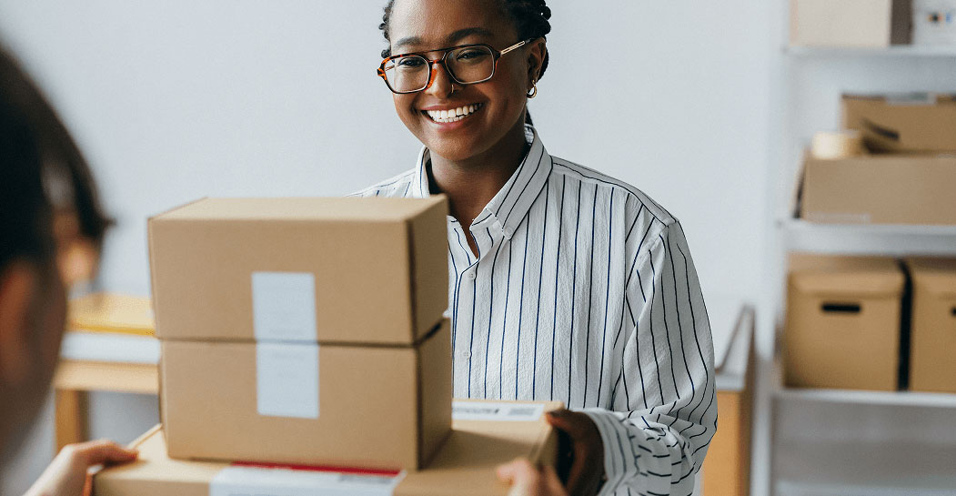 A small business owner handing off packages to be shipped for delivery.