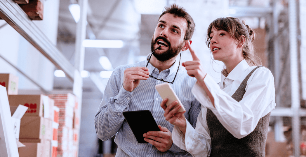 Two young supply chain managers talking together in a warehouse.