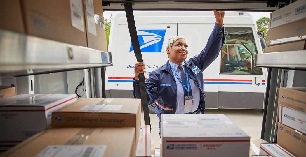 A mail carrier handling packages from a delivery truck.