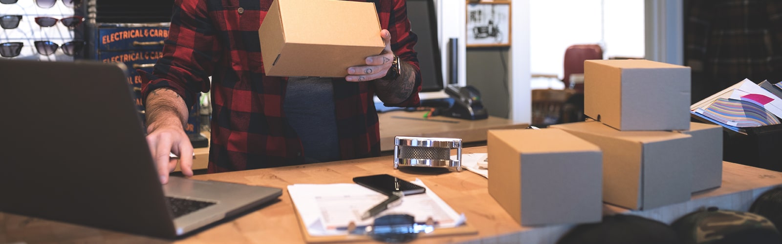 A professional holding a package in front of a laptop.